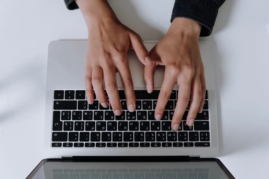 Ruke iznad tastature laptopa, pogled odozgo